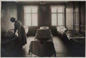 En kvinde reder en seng i en sovesal for kvinder og børn, Kvindehjemmets historie