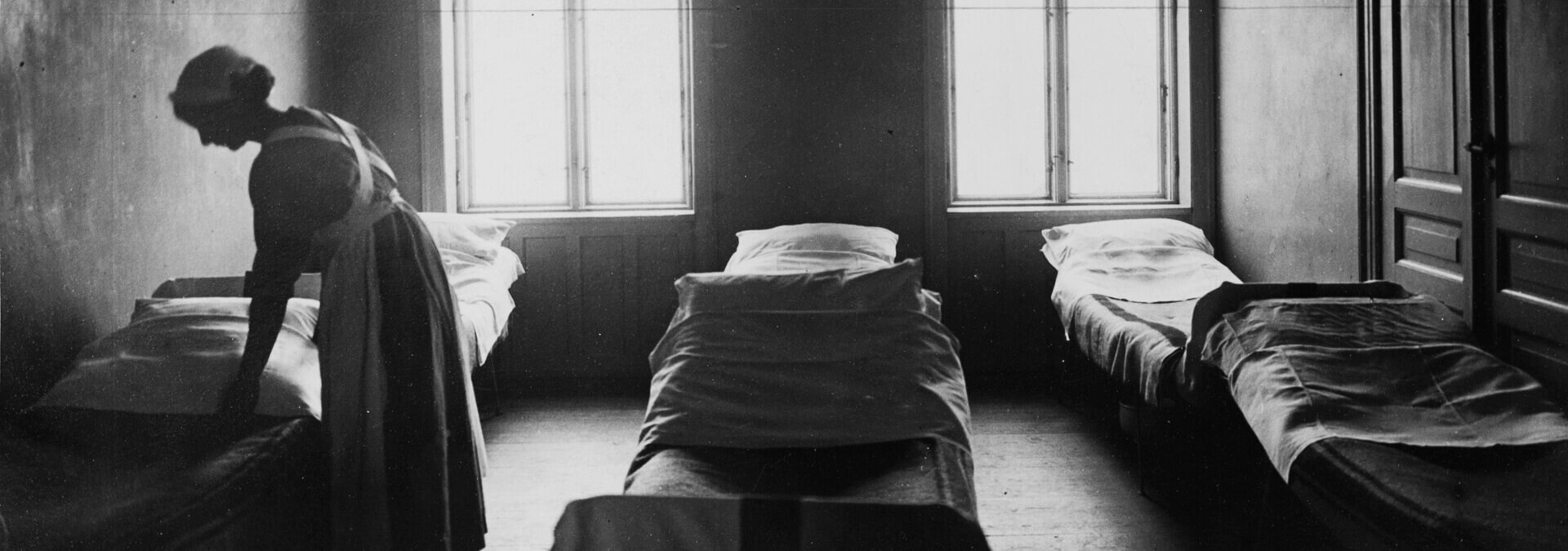 En kvinde reder en seng på en sovesal for kvinder og børn, Kvindehjemmets historie