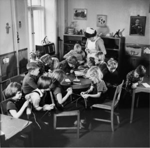 Børnene i børnehaven sidder rundt om et bord og fletter, Kvindehjemmets historie